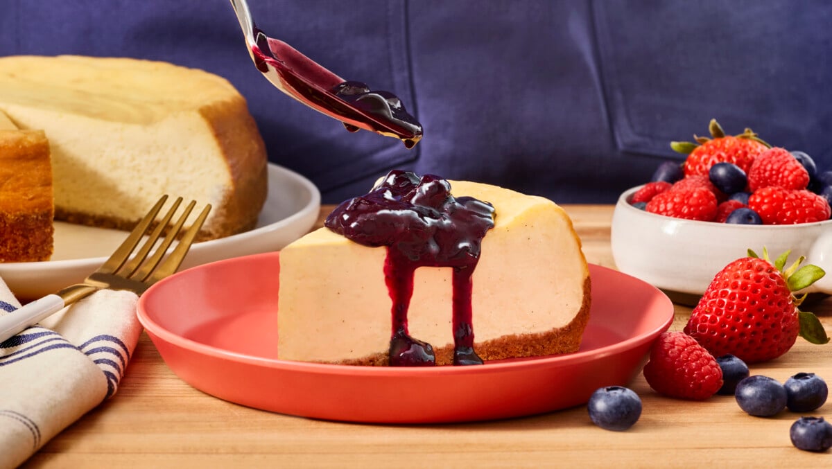 Blueberry compote being spooned over a New York style cheesecake.