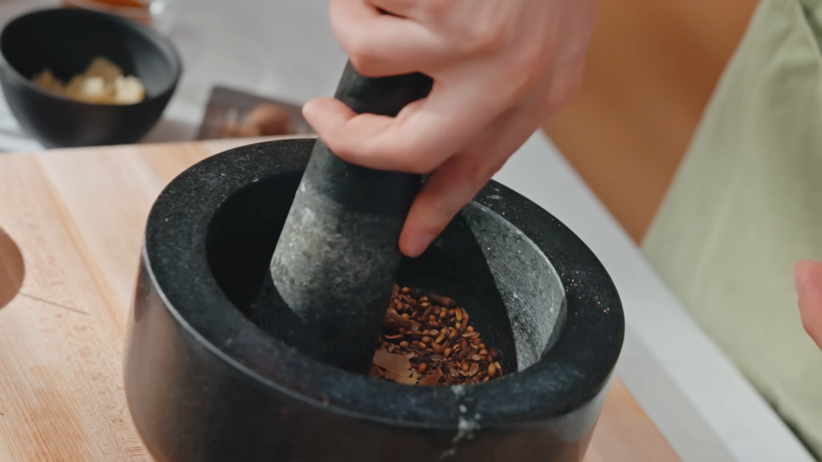 Spices being ground up in a bowl by hand.