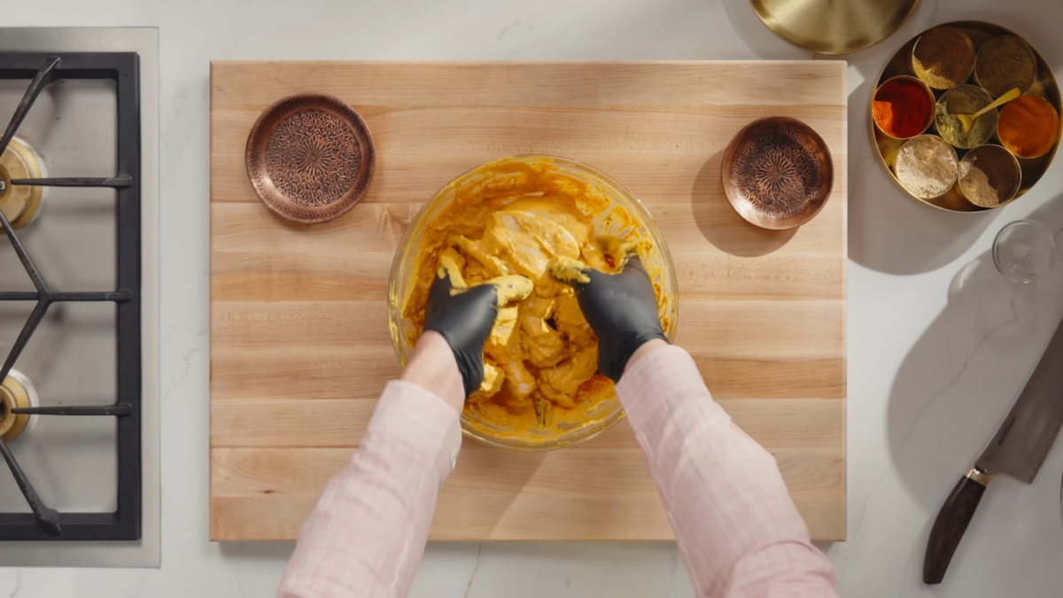 A man marinading chicken breasts in a yogurt sauce.