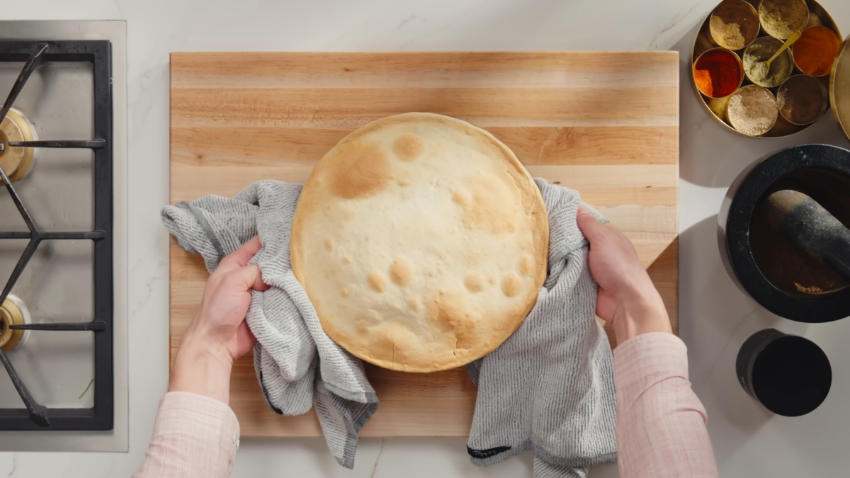 A man holding a pot of chicken biryani with crust top.