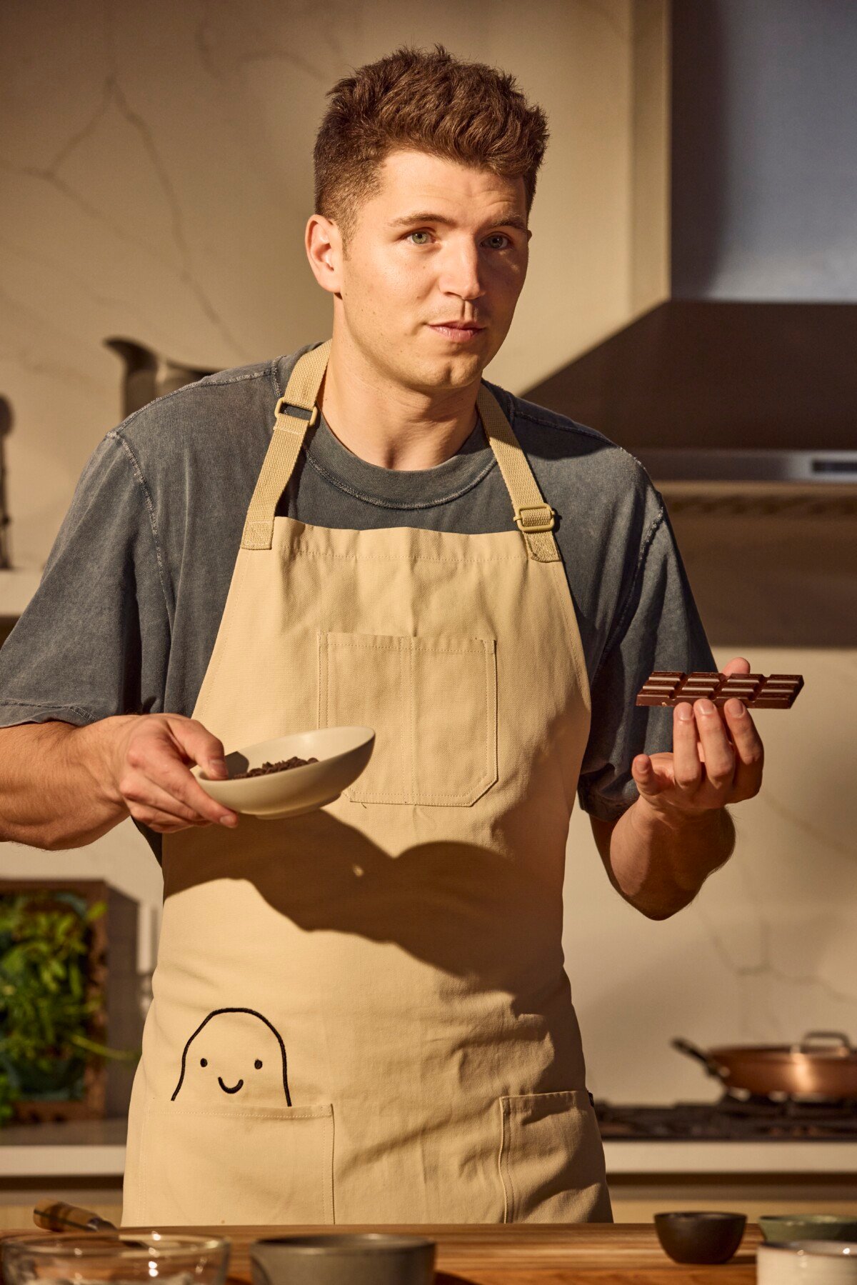 A male chef holding two different types of chocolate.