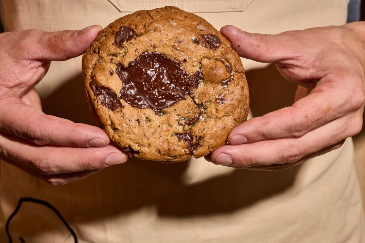 A chef holding a chocolate chip cookie.