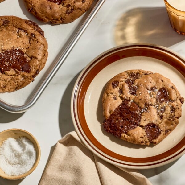 Brown butter chocolate chip cookies on a baking sheet and one on a plate.