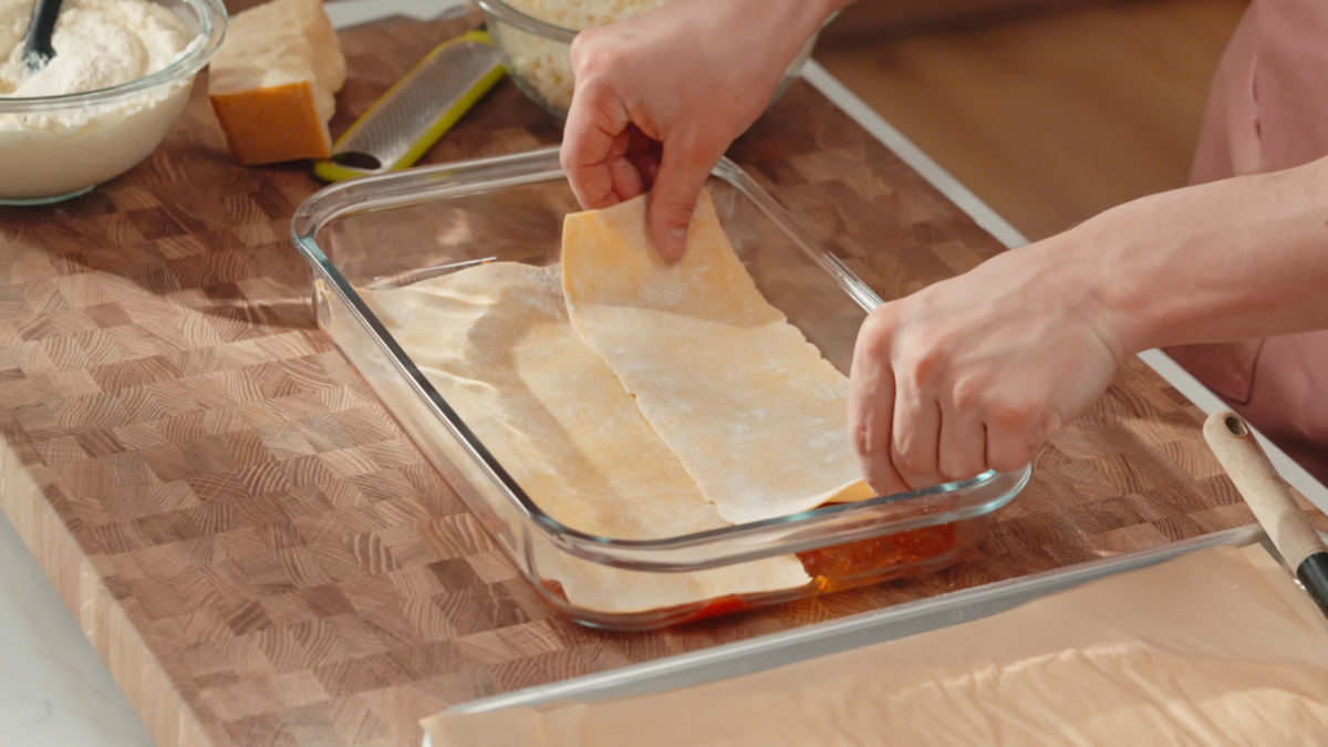 Homemade lasagna pasta sheets placed on the bottom of a glass pan.