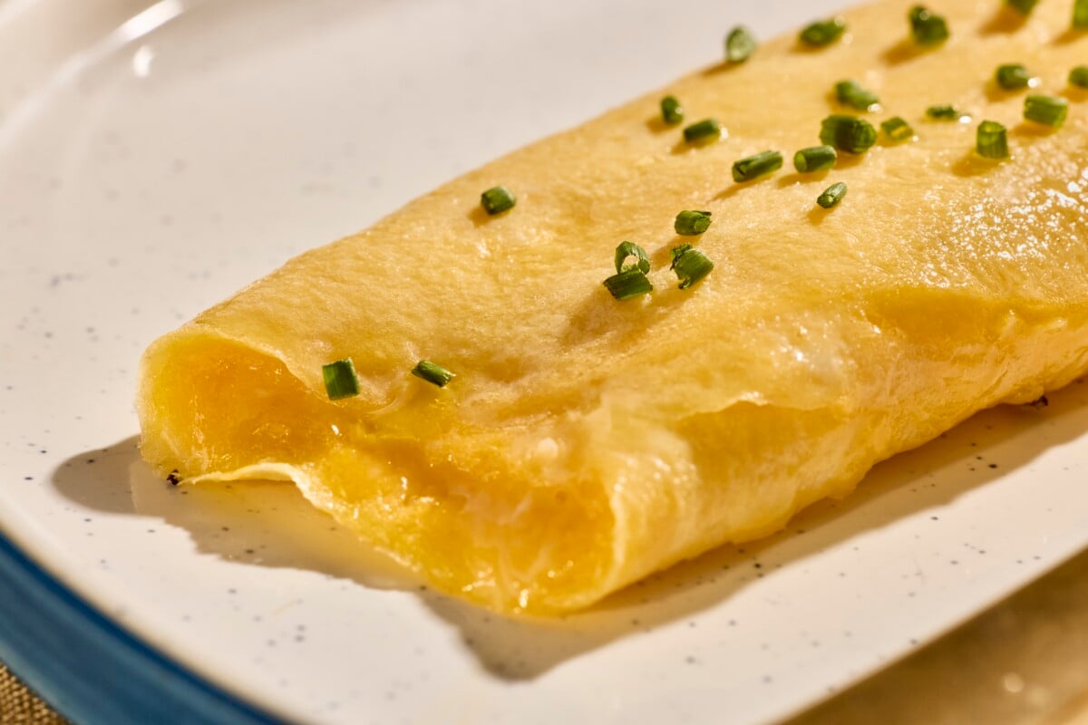 French omelette on a plate topped with chives.