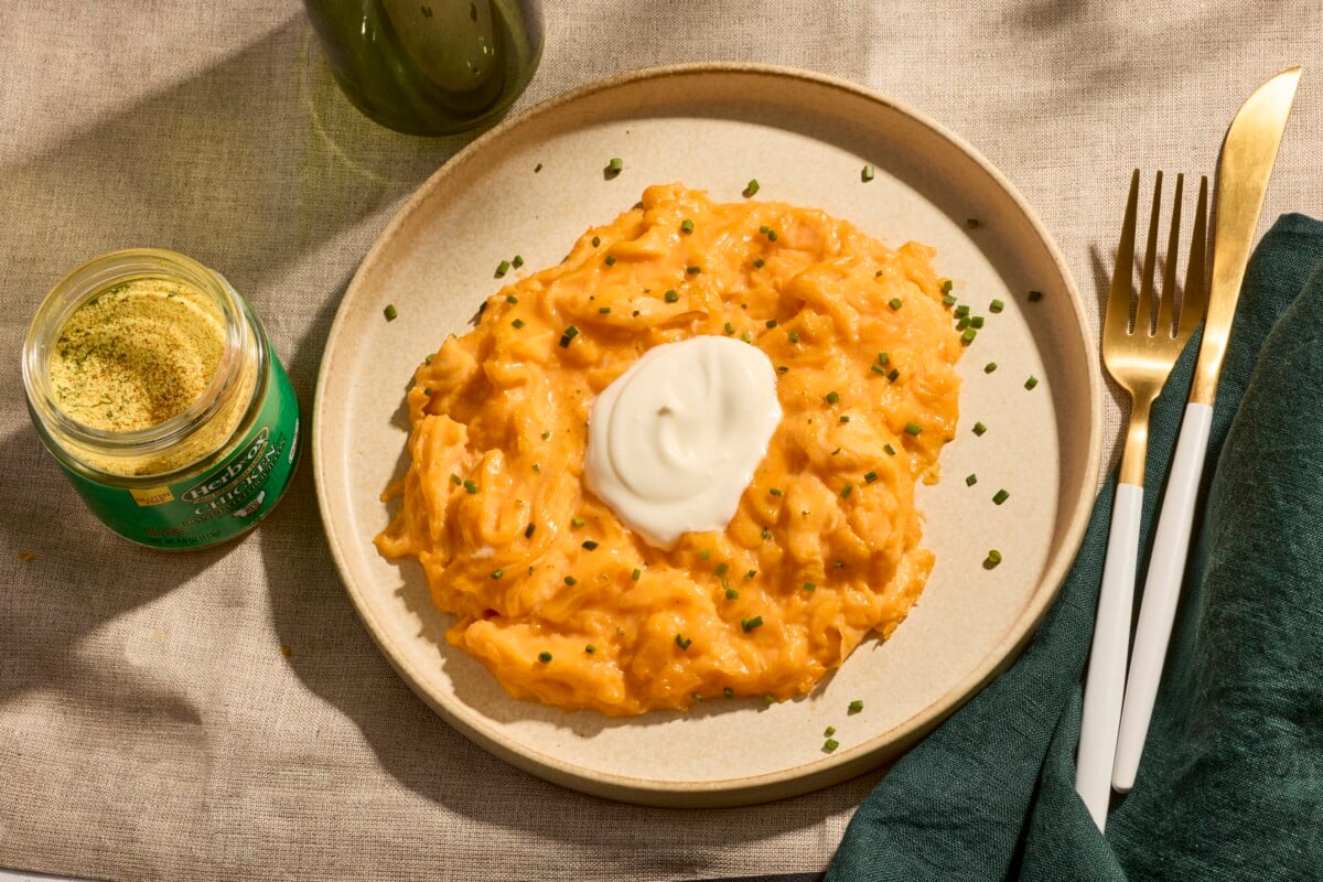 A plate of soft scrambled eggs topped with crème fraiche and chives.