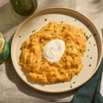 A plate of soft scrambled eggs topped with crème fraiche and chives.