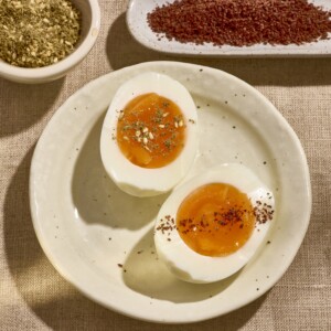 Soft boiled egg sliced in half on a plate topped with spices.