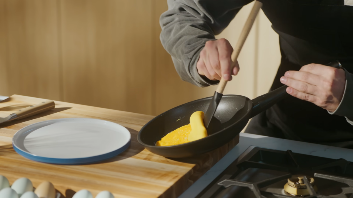 A man flipping an omelette in a pan.