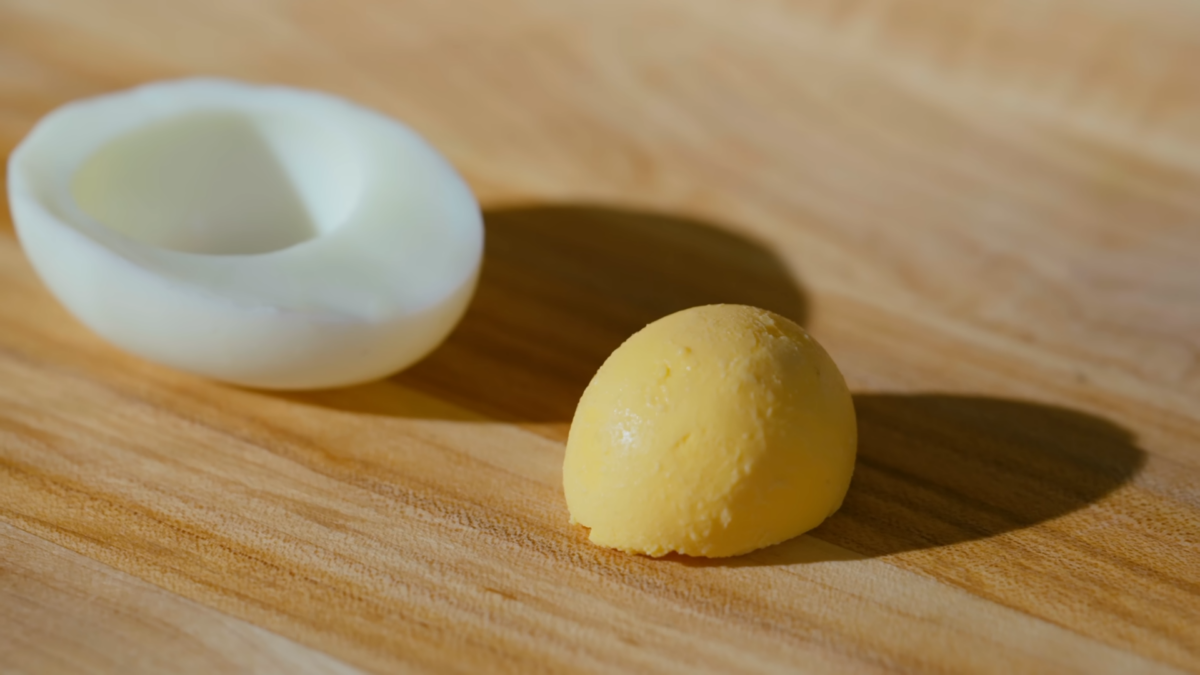 A hard boiled egg white and yolk on a wooden cutting board. 