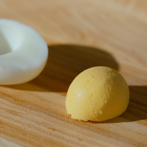 A hard boiled egg white and yolk on a wooden cutting board.
