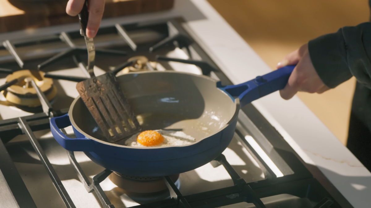 An egg in a frying pan about to be flipped with a spatula.
