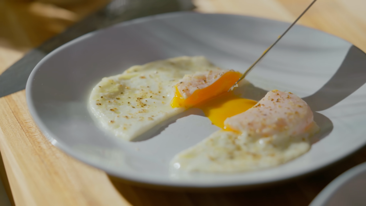 An over easy cut in half with runny yolk served on a plate.