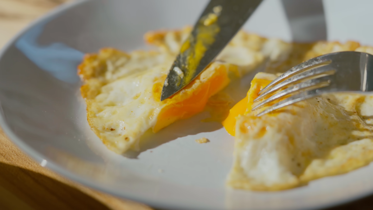 An over medium egg cut in half on a plate.