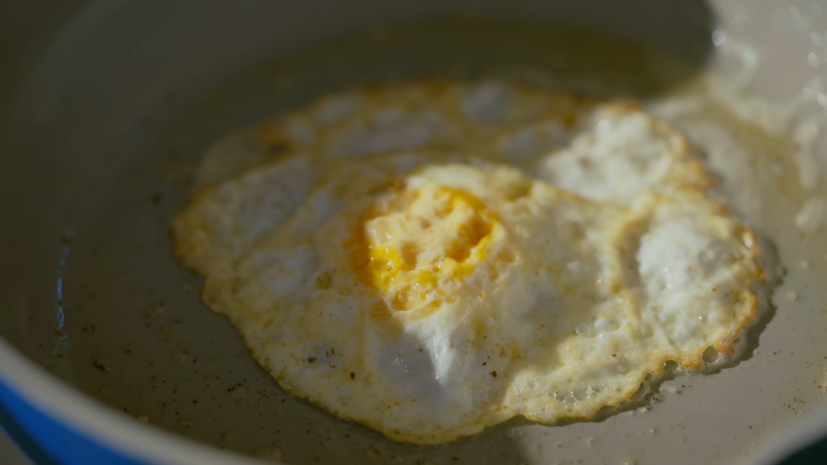 An over medium egg cooking on a skillet.