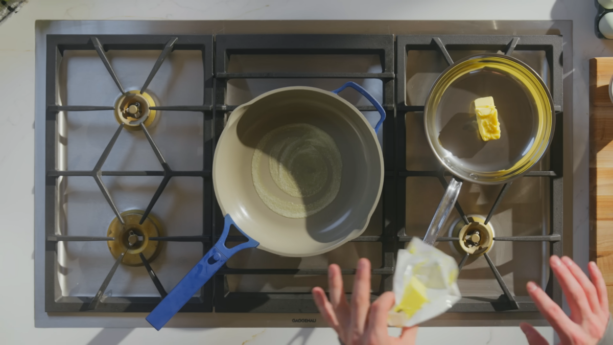 A pan with melted butter and another pan with solid butter on a stove.