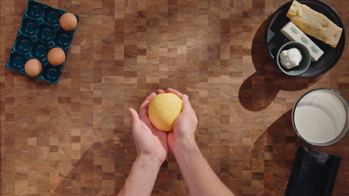 A man holding a ball of kneaded dough.