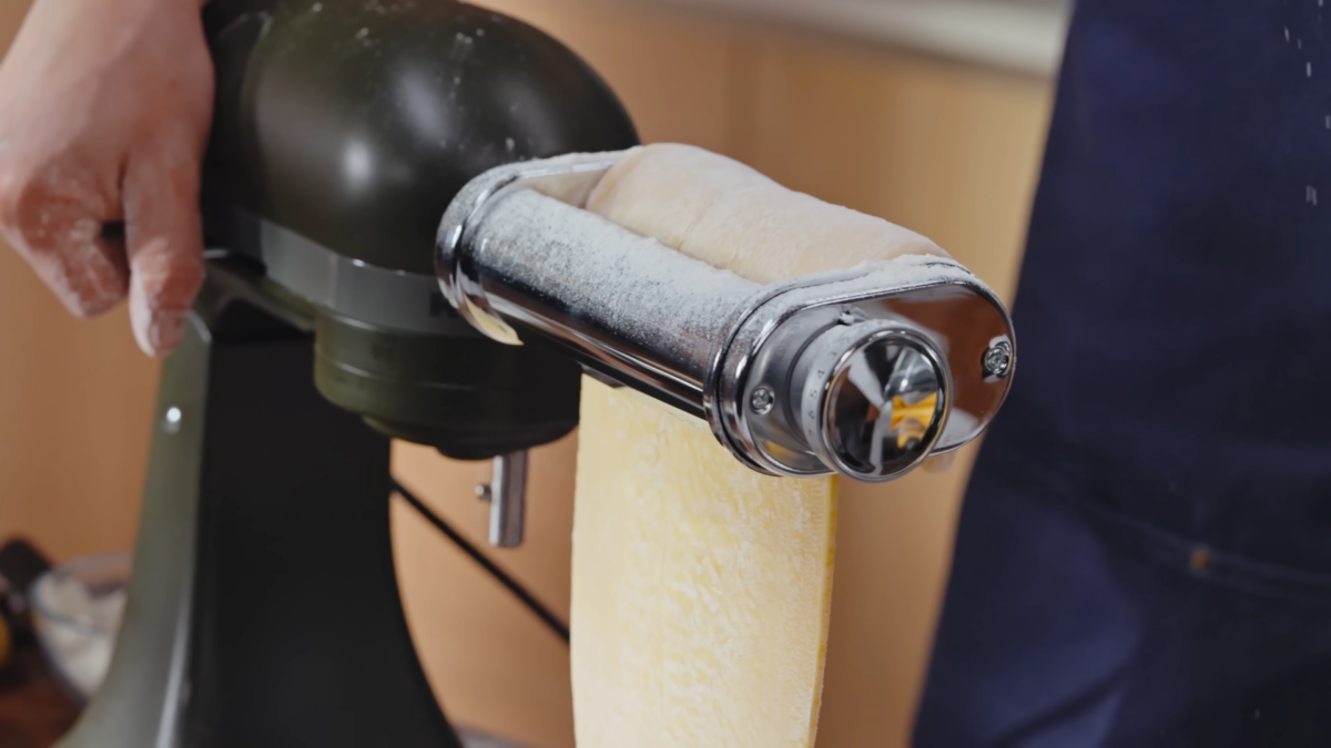 Dough being pressed through a pasta machine.
