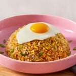 A bowl of egg fried rice topped with a fried egg.