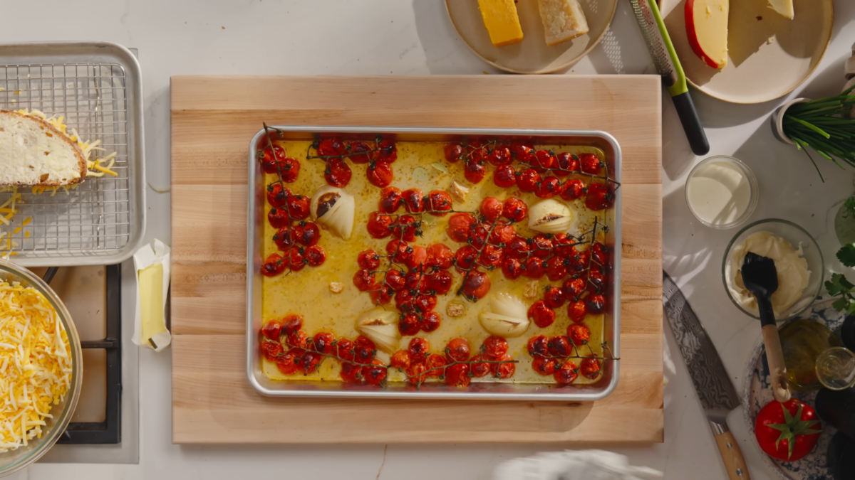 A baking sheet of roasted tomatoes, onions, and garlic.