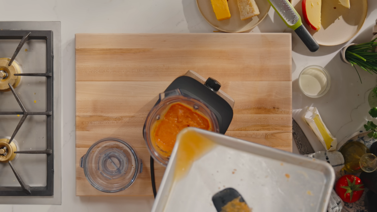 Hot water being poured into a blender of tomato soup.