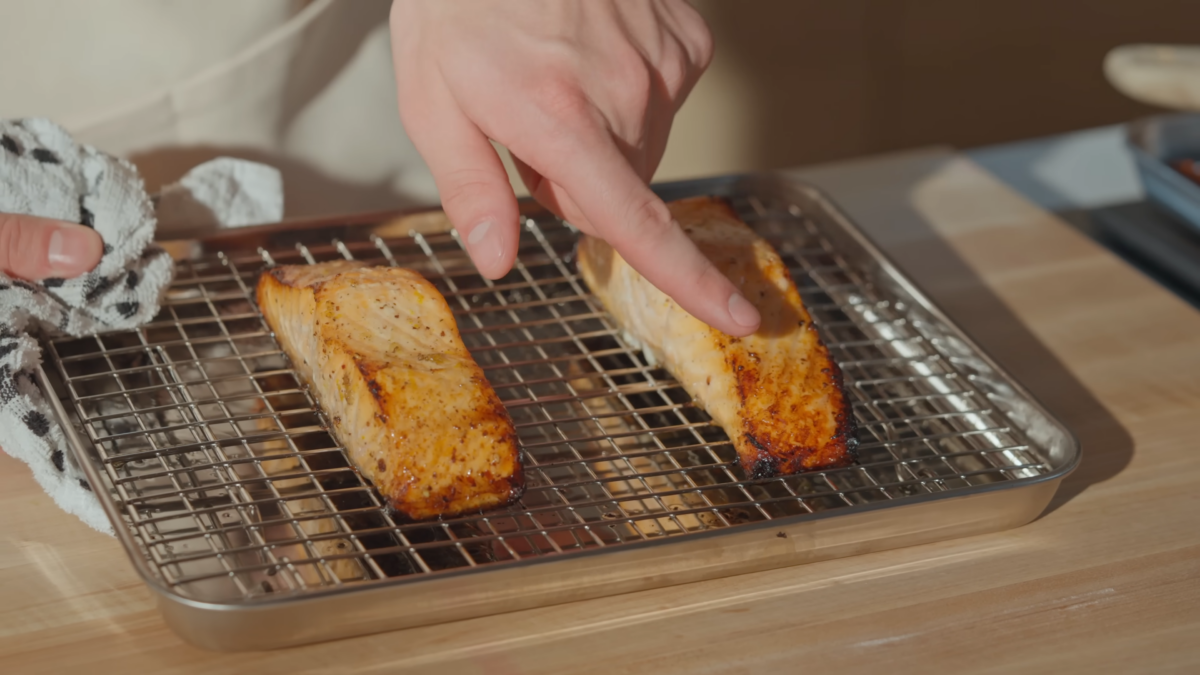 Two pieces of cooked salmon on a wire rack.