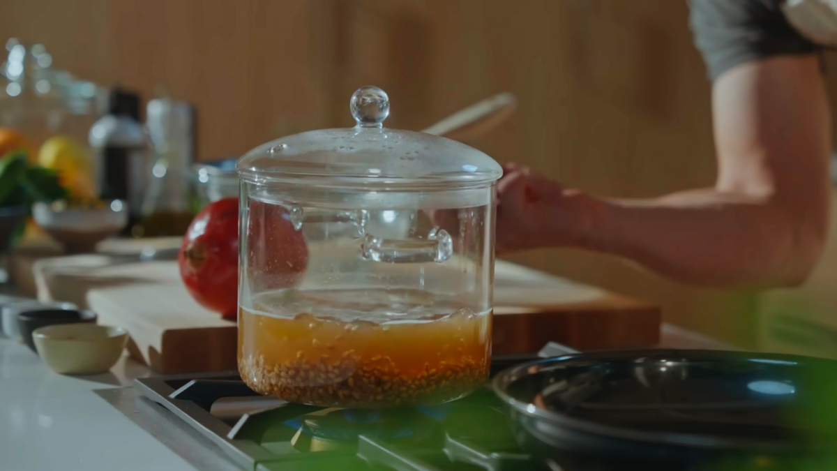 Farro grain cooking in a glass pot of broth.