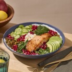 A farro grain bowl with salmon, cucumbers, avocado, feta, and pomegranate seeds.