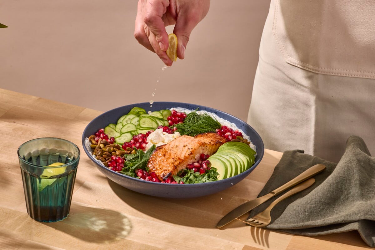 A grain bowl being topped with lemon juice. 