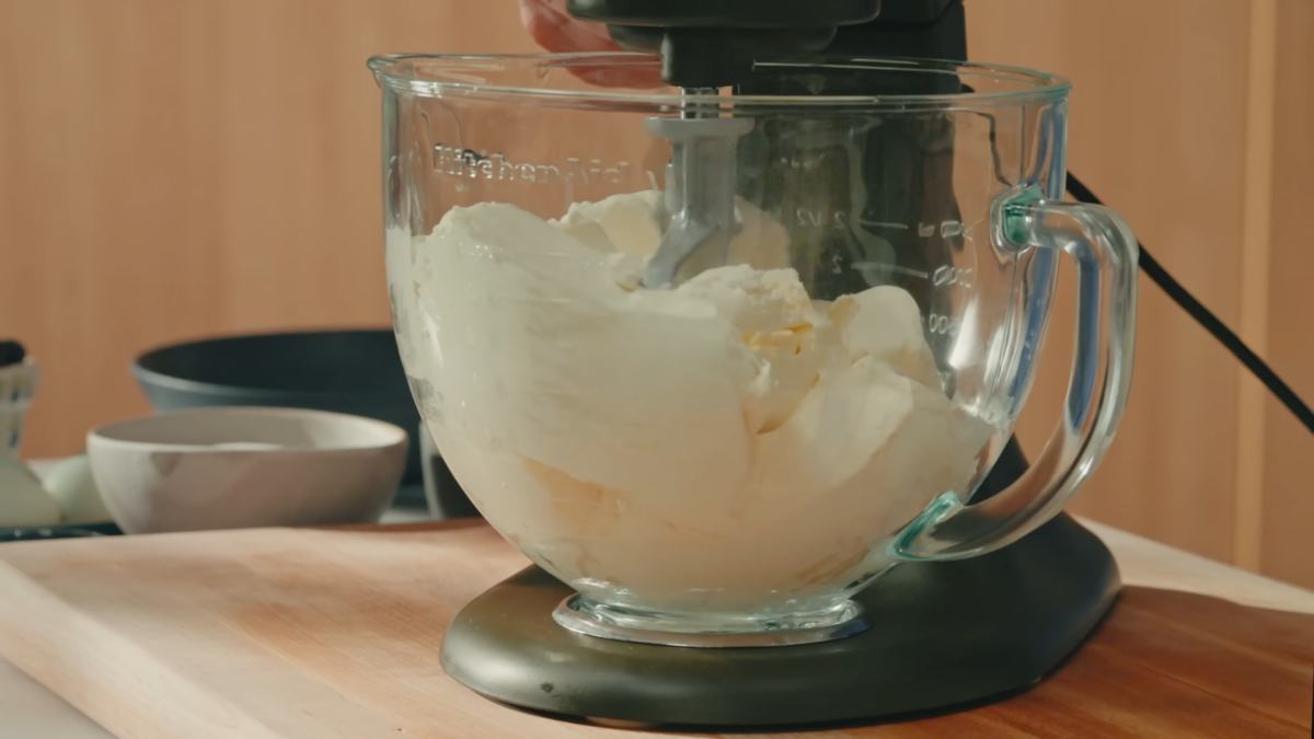 Cream cheese mixing in a glass bowl.