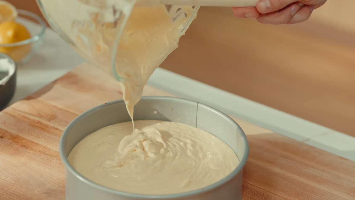 Cheesecake filling being poured into a baking dish.