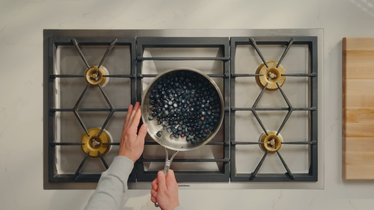 A pan of blueberries with water and sugar on a stove.