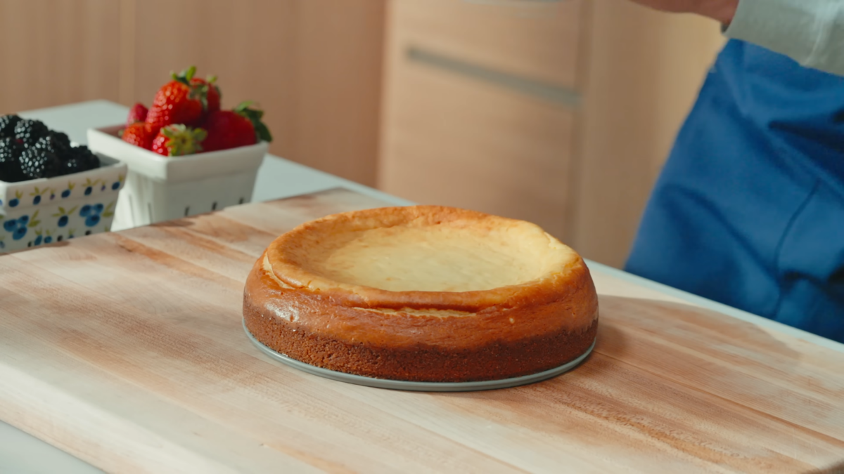 A baked cheesecake on a wooden cutting board.