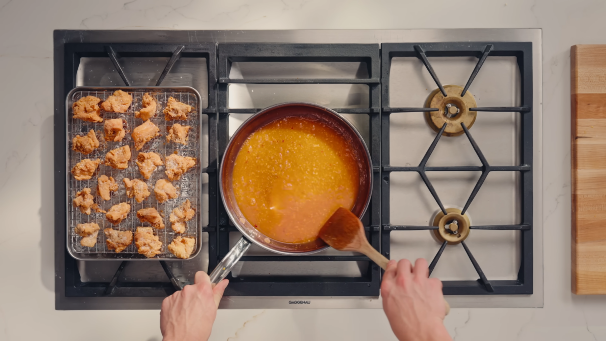 A man making orange sauce over a stove.