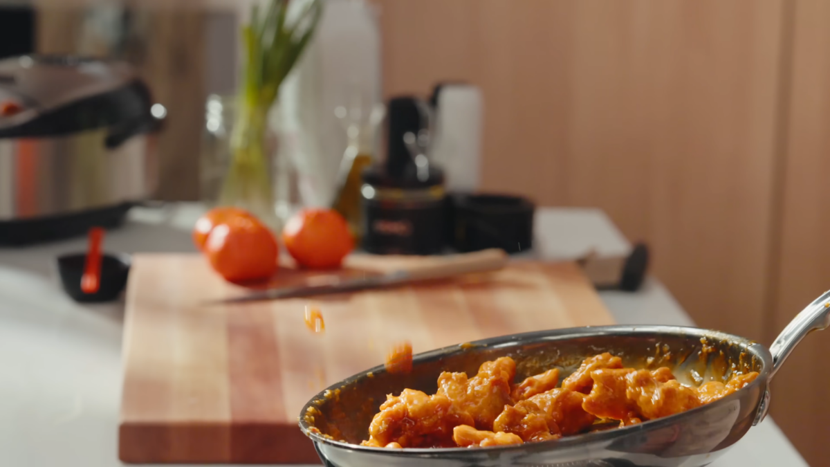 Orange chicken tossed in a pan.