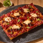 A sheet pan pizza topped with ricotta and fresh basil.