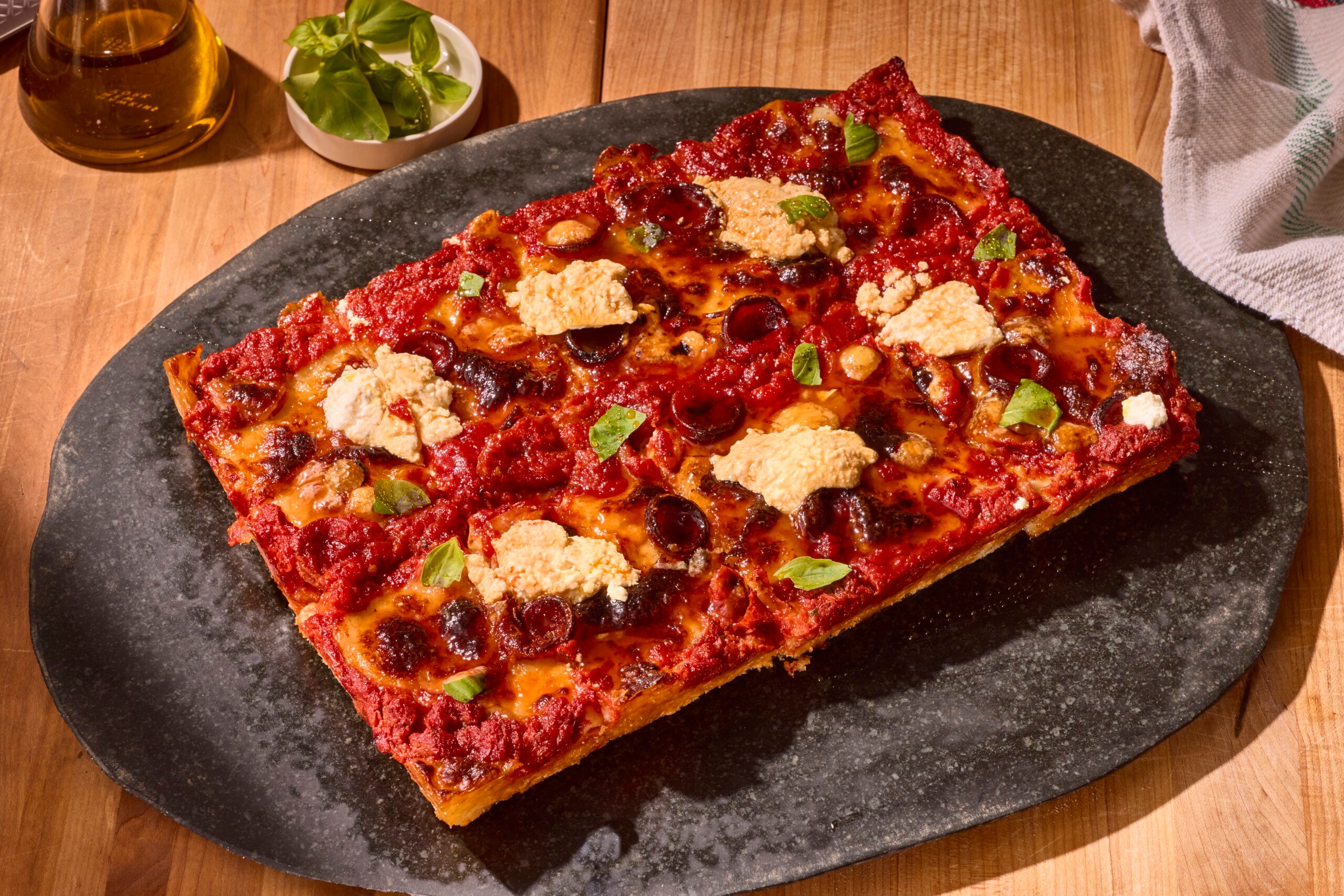 A sheet pan pizza topped with ricotta and fresh basil.