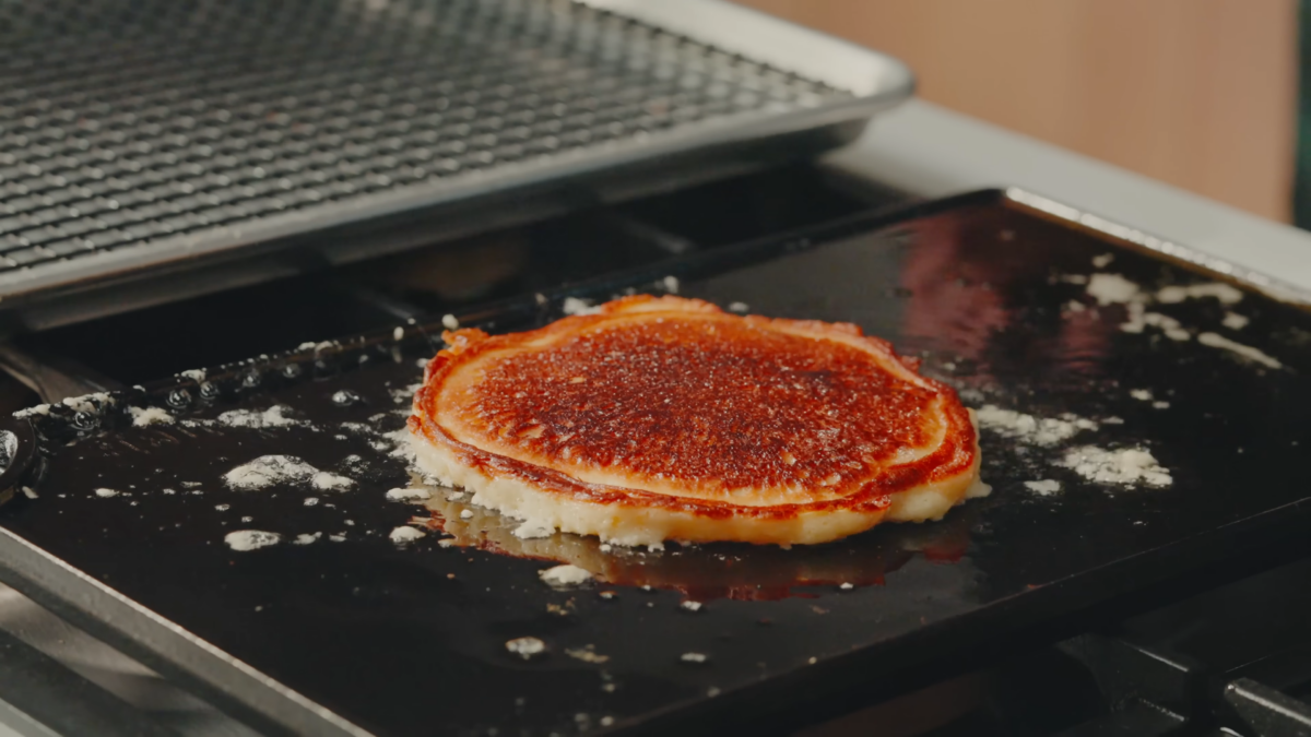 A pancake with crispy edges on a cast iron griddle.