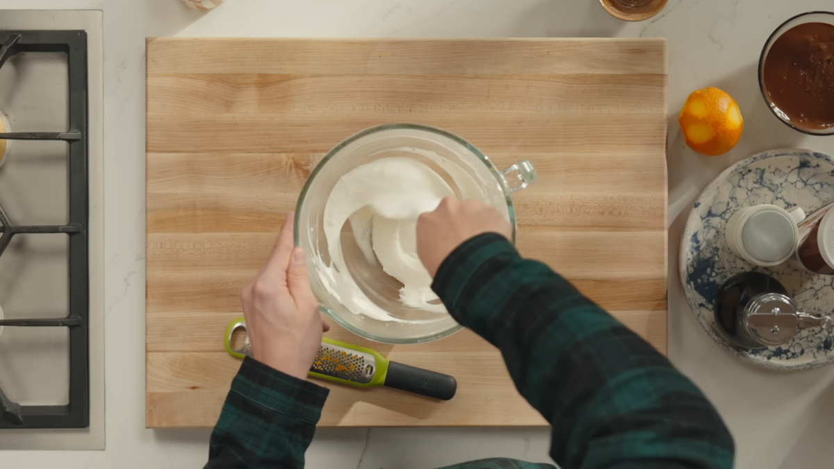 Orange zest being folded into a bowl of whipped cream.