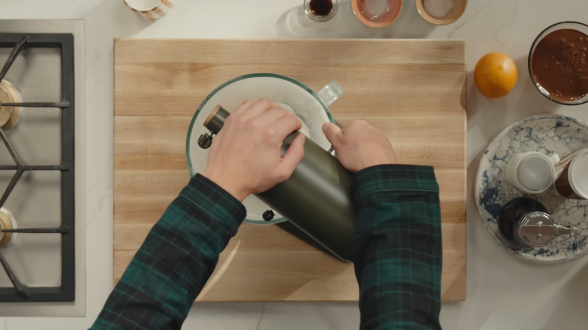 Two male hands holding onto the top of a green stand mixer.