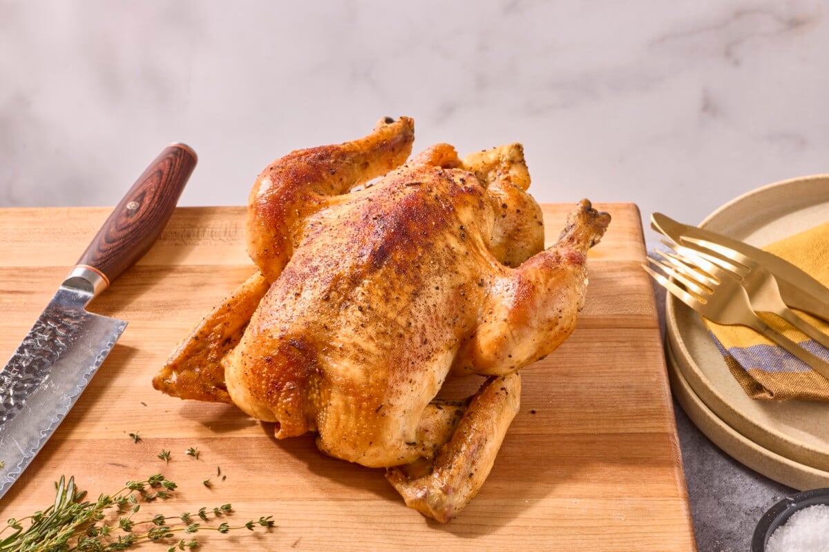 A rotisserie style whole roasted chicken on a cutting board.