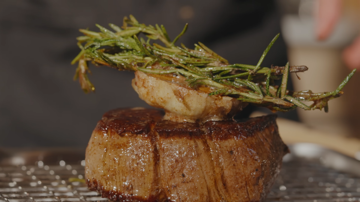 A small steak with garlic and herbs on top.