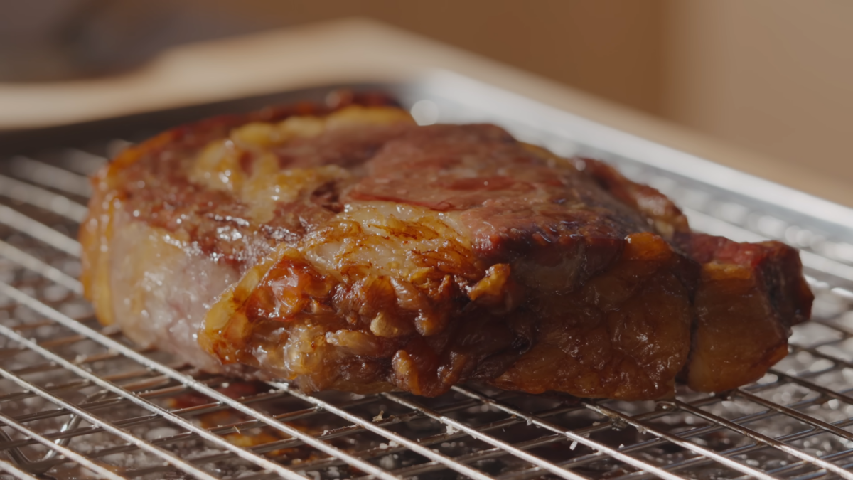 A cooked steak on a wire rack.