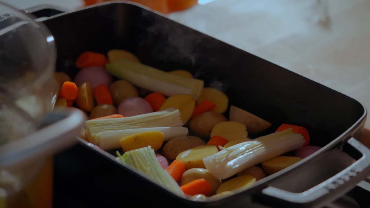 A large deep pan with vegetables and broth.
