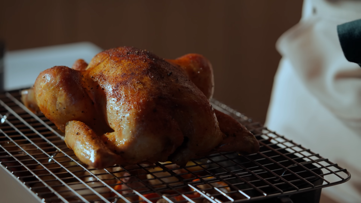 A cooked rotisserie chicken on a wire rack.