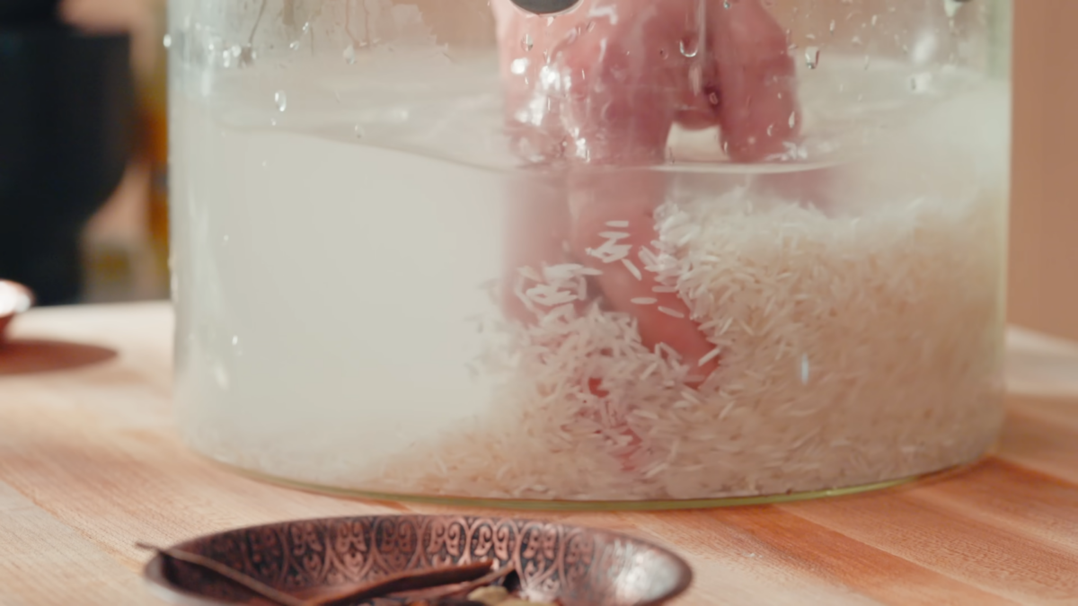 A man rinsing rice in a glass pot.
