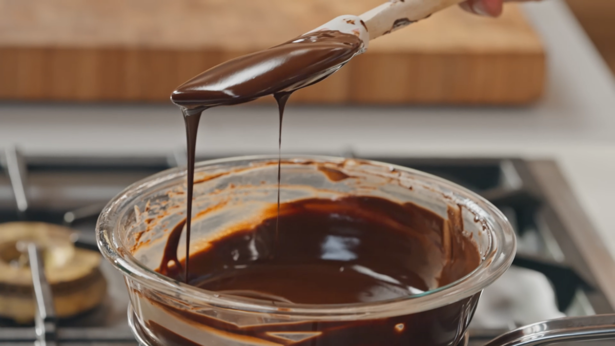 Melted chocolate scooped out of a bowl with a spatula.