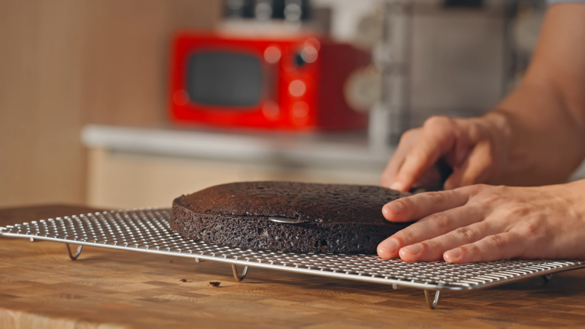 A man trimming a chocolate cake.