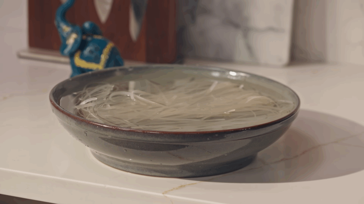 A bow of rice noodles submerged in water.