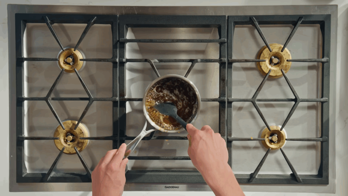 A man stirring a pot of simmering sauce.